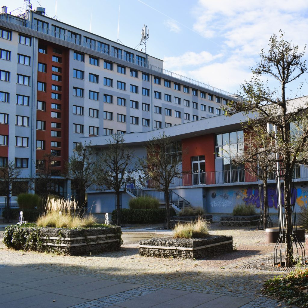 budynek Centrum Aktywności Studenckiej i Doktoranckiej przy akademiku Dwudziestolatka, budynek jednopiętrowy, widoczne w centrum zdjęcia schody prowadzą na tzw. "wysoki parter"; wejścia głównego nie widać (wnęka między akademikiem a budynkiem, nad garażem)